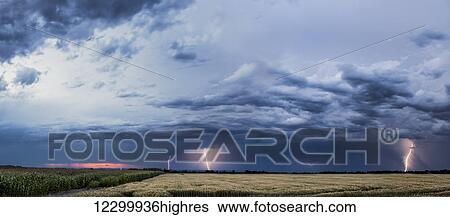 Stock Photograph - Storm clouds and lightning strikes over a rural landscape; Thunder Bay, Ontario, Canada. Fotosearch