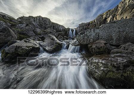 Stream flows over a waterfall and through the rocks along the eastern coast of Iceland; Iceland View Large Photo Image Stock Photograph - Stream flows over a waterfall and through the rocks along the eastern coast of Iceland; Iceland. Fotosearch