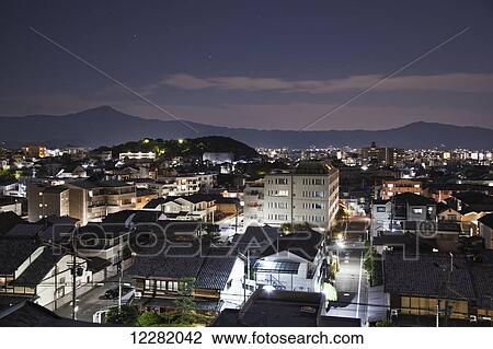 Streets and buildings illuminated at dusk, with silhouetted mountains in the distance; Kyoto, Japan View Large Photo Image Stock Image - Streets and buildings illuminated at dusk, with silhouetted mountains in the distance; Kyoto, Japan. Fotosearch