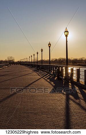 Stock Photograph - Sun setting behind lampposts, Liberty State Park; Jersey City, New Jersey, United States of America. Fotosearch