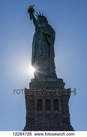 Sun setting behind the Statue of Liberty, Liberty Island; New York City, New York, United States of America View Large Photo Image Stock Photograph - Sun setting behind the Statue of Liberty, Liberty Island; New York City, New York, United States of America. Fotosearch