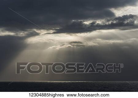 Stock Photograph - Sunlight breaks through the clouds over the ocean on the Oregon coast; Cannon Beach, Oregon, United States of America. Fotosearch