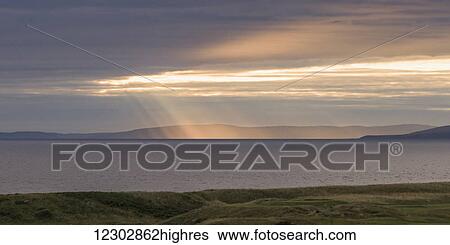 Sunlight shining through clouds onto the coastline; Turnery, Scotland View Large Photo Image Stock Photograph - Sunlight shining through clouds onto the coastline; Turnery, Scotland. Fotosearch