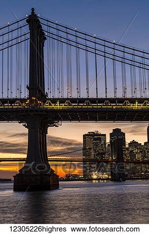 Stock Photograph - Sunset behind Manhattan and Brooklyn Bridges; New York City, New York, United States of America. Fotosearch