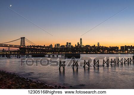 Stock Photograph - Sunset over Lower Manhattan near World Trade Center and Williamsberg Bridge; Brooklyn, New York, United States of America. Fotosearch