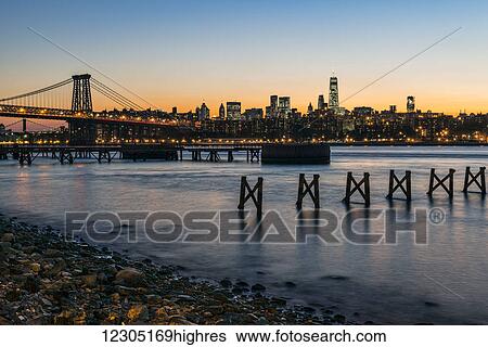 Stock Photograph - Sunset over Lower Manhattan near World Trade Center and Williamsberg Bridge; Brooklyn, New York, United States of America. Fotosearch