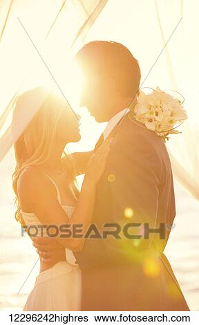 Stock Photograph - Sunset Wedding. Bride and Groom at Sunset on Wedding Day. Fotosearch