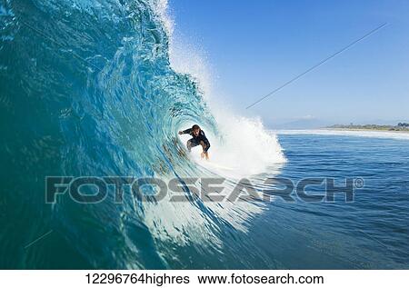 Stock Photograph - Surfer on Blue Ocean Wave in the Tube Getting Barreled. Fotosearch