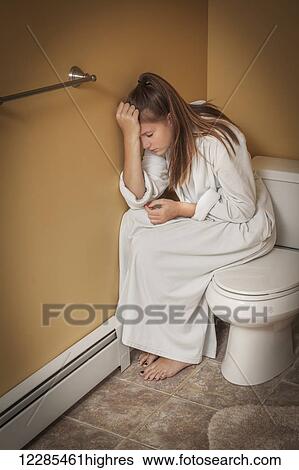 Teenage girl sitting in the bathroom on the toilet seat looking unhappy View Large Photo Image Stock Photograph - Teenage girl sitting in the bathroom on the toilet seat looking unhappy. Fotosearch