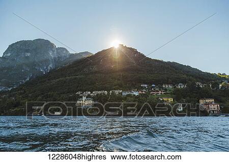 The afternoon sun setting over the mountain landscape in Lake Como; Lombardy, Italy View Large Photo Image Stock Photograph - The afternoon sun setting over the mountain landscape in Lake Como; Lombardy, Italy. Fotosearch