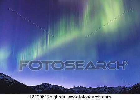 Stock Photograph - The aurora borealis dances over the Chugach Mountains just before dawn near Girdwood, Alaska.. Fotosearch