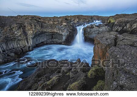 Stock Photograph - The basalt column and waterfall known as Aldeyjarfoss in Northern Iceland, a person stands at the top and photographs them; Iceland. Fotosearch