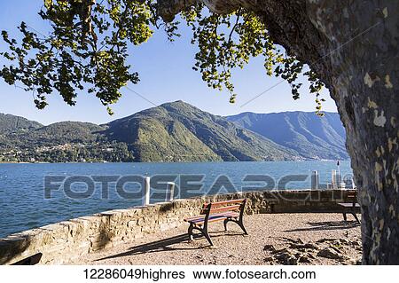 Stock Photograph - The end of the waterfront where you can sit and enjoy this mountain viewpoint of Lake Como; Cadenabbia, Lombardy, Italy. Fotosearch