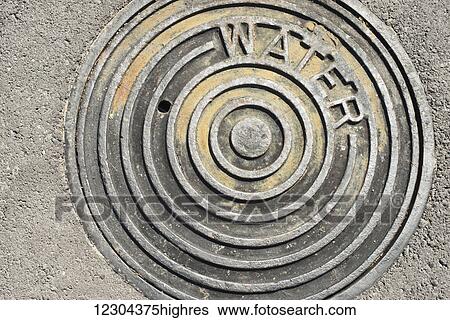 The hot sun beats down on a manhole cover with the word 'water' engraved on it; Waikaloa, Island of Hawaii, Hawaii, United States of America View Large Photo Image Stock Photograph - The hot sun beats down on a manhole cover with the word 'water' engraved on it; Waikaloa, Island of Hawaii, Hawaii, United States of America. Fotosearch