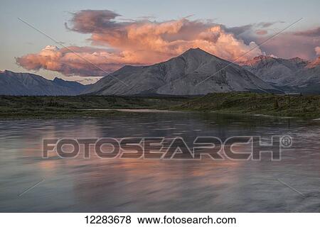 The midnight sun shines on the mountains and clouds lining the Wind River in the Peel watershed; Yukon, Canada View Large Photo Image Stock Photo - The midnight sun shines on the mountains and clouds lining the Wind River in the Peel watershed; Yukon, Canada. Fotosearch