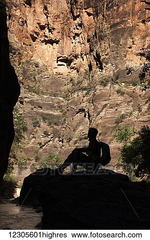Stock Photograph - The shadow of a man sitting on a rock with a backpack looking upwards, Bryce Canyon National Park; Utah, United States of America. Fotosearch