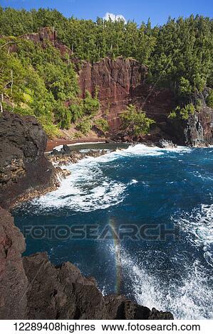 Stock Photograph - The stunning Kaihulu Bay with a rainbow splash; Hana, Maui, Hawaii, United States of America. Fotosearch
