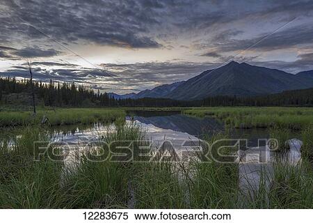 Stock Photography - The sun sets over a small pond that lies alongside the Wind River in the Peel Watershed; Yukon, Canada. Fotosearch