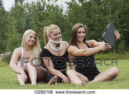 Three friends taking a team selfie outdoors in a park with a mobile device; Edmonton, Alberta, Canada View Large Photo Image Stock Photo - Three friends taking a team selfie outdoors in a park with a mobile device; Edmonton, Alberta, Canada. Fotosearch