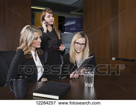 Stock Photo - Three professional business women during a training session in a boardroom; St. Albert, Alberta, Canada. Fotosearch