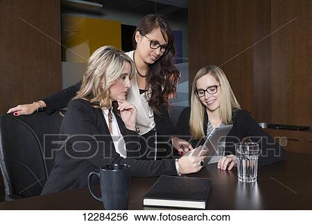 Stock Photograph - Three professional business women during a training session in a boardroom; St. Albert, Alberta, Canada. Fotosearch