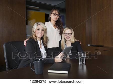 Stock Photography - Three professional business women during a training session in a boardroom; St. Albert, Alberta, Canada. Fotosearch