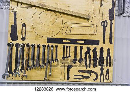 Stock Photograph - Tools and their outlines hang on a wall inside an electrical power plant, Sand Point, Southwestern Alaska, USA, Summer. Fotosearch