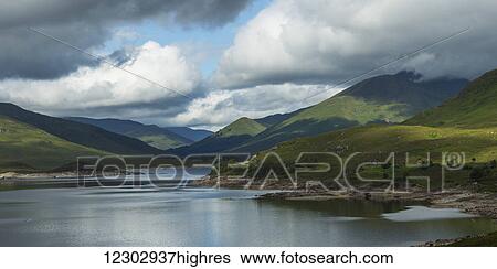 Stock Photograph - Tranquil water in a mountainous landscape under a cloudy sky; Scotland. Fotosearch
