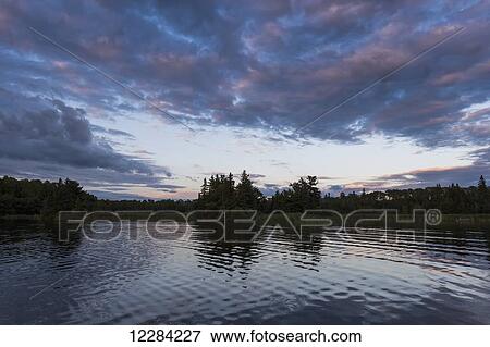 Tranquil water of a lake at sunset; Lake of the Woods, Ontario, Canada View Large Photo Image Stock Photo - Tranquil water of a lake at sunset; Lake of the Woods, Ontario, Canada. Fotosearch