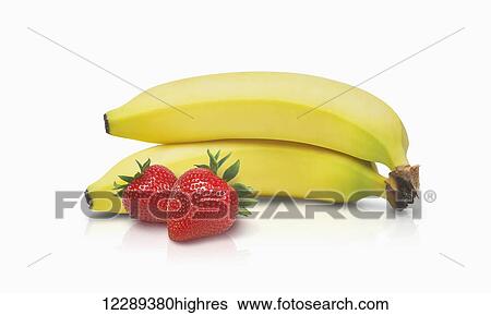 Stock Photograph - Two bananas and two strawberries on a white background; Toronto, Ontario, Canada. Fotosearch