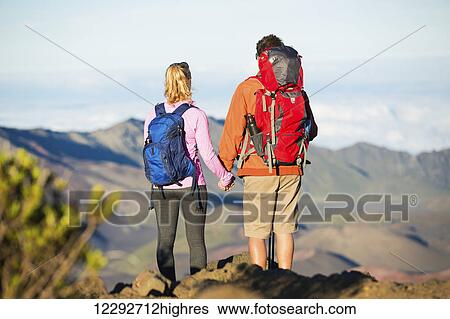 Two hikers relaxing enjoying the amazing view from the mountain top. Looking out over the volcano crater. View Large Photo Image Stock Photograph - Two hikers relaxing enjoying the amazing view from the mountain top. Looking out over the volcano crater.. Fotosearch