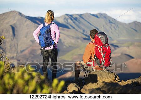 Two hikers relaxing enjoying the amazing view from the mountain top. View Large Photo Image Stock Photograph - Two hikers relaxing enjoying the amazing view from the mountain top.. Fotosearch