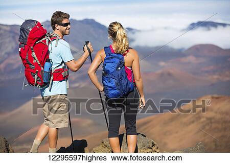 Two hikers relaxing enjoying the amazing view from the mountain top. Looking out over the volcano crater. View Large Photo Image Stock Photograph - Two hikers relaxing enjoying the amazing view from the mountain top. Looking out over the volcano crater.. Fotosearch