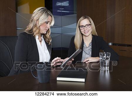 Picture - Two professional business women during a training session in a boardroom; St. Albert, Alberta, Canada. Fotosearch