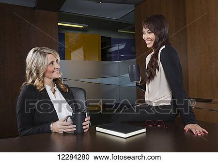 Stock Image - Two professional business women during a casual meeting in a boardroom; St. Albert, Alberta, Canada. Fotosearch