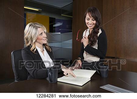 Two professional business women during a casual meeting in a boardroom; St. Albert, Alberta, Canada View Large Photo Image Stock Image - Two professional business women during a casual meeting in a boardroom; St. Albert, Alberta, Canada. Fotosearch