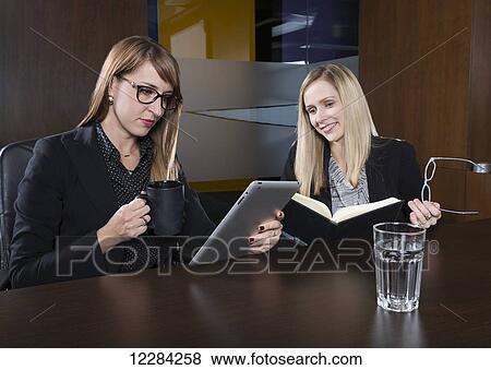 Two professional business women during a training session in a boardroom; St. Albert, Alberta, Canada View Large Photo Image Stock Photo - Two professional business women during a training session in a boardroom; St. Albert, Alberta, Canada. Fotosearch