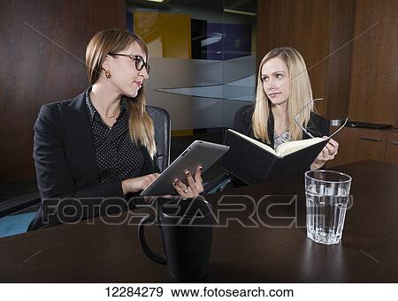Two professional business women during a training session in a boardroom; St. Albert, Alberta, Canada View Large Photo Image Stock Photo - Two professional business women during a training session in a boardroom; St. Albert, Alberta, Canada. Fotosearch