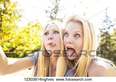 Two sisters having fun outdoors in a city park in autumn taking selfies of themselves and making funny faces; Edmonton, Alberta, Canada View Large Photo Image Stock Photograph - Two sisters having fun outdoors in a city park in autumn taking selfies of themselves and making funny faces; Edmonton, Alberta, Canada. Fotosearch