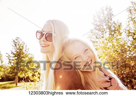 Stock Photograph - Two sisters having fun together in a city park during autumn and posing for the camera; Edmonton, Alberta, Canada. Fotosearch