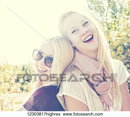 Stock Photograph - Two sisters having fun together in a city park during autumn and posing for the camera; Edmonton, Alberta, Canada. Fotosearch