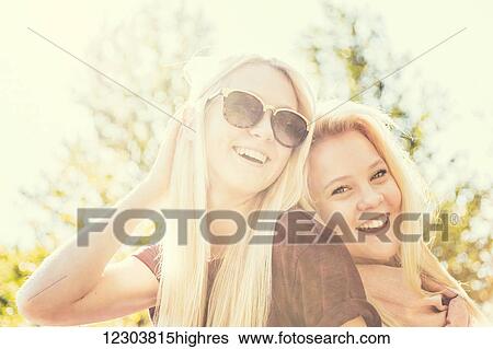 Stock Photograph - Two sisters having fun together outdoors in a city park in autumn and posing for the camera; Edmonton, Alberta, Canada. Fotosearch