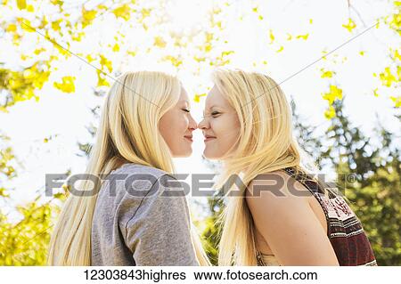 Stock Photograph - Two sisters in a city park in autumn being silly and touching noses; Edmonton, Alberta, Canada. Fotosearch