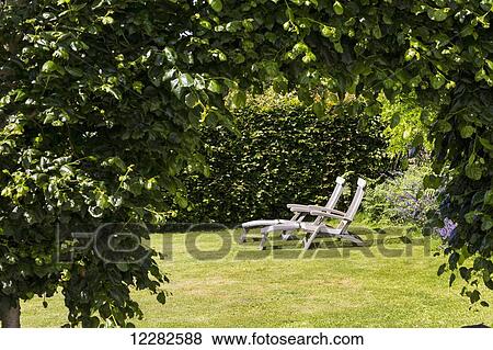 Two wooden lounge chairs on a lawn framed by bushes; Carhaix-Plouguer, Brittany, France View Large Photo Image Stock Photo - Two wooden lounge chairs on a lawn framed by bushes; Carhaix-Plouguer, Brittany, France. Fotosearch