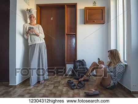 Two young women in their apartment using their smart phones; Sagres, Portugal View Large Photo Image Stock Photograph - Two young women in their apartment using their smart phones; Sagres, Portugal. Fotosearch