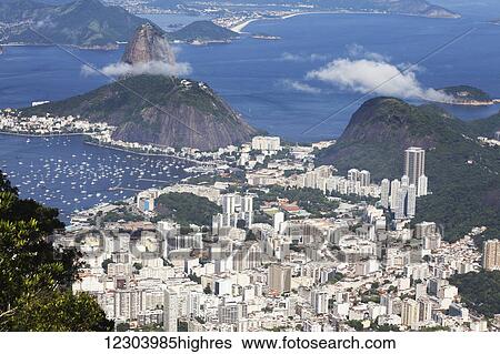 Stock Photograph - View of Rio and Sugarloaf Mountain from Christ the Redeemer statue, Corcovado mountain, Tijaca National Park; Rio de Janeiro, Brazil. Fotosearch