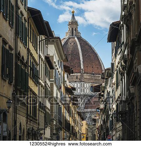 Stock Photograph - View of the dome roof of a church past rows of residential and retail buildings; Florence, Toscana, Italy. Fotosearch