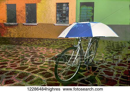 Stock Photograph - Wall art of bicycle protected by blue and white umbrella in front of colourful buildings on Burano Island on canal in Venice, Italy. Fotosearch