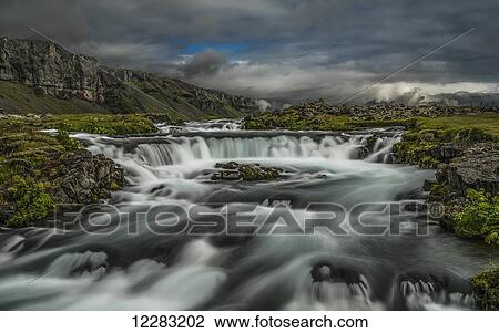 Water flowing over a rugged landscape under a cloudy sky; Iceland View Large Photo Image Stock Image - Water flowing over a rugged landscape under a cloudy sky; Iceland. Fotosearch