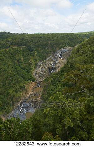 Stock Image - Water streaming and pooling over rocks between green foliage; Australia. Fotosearch